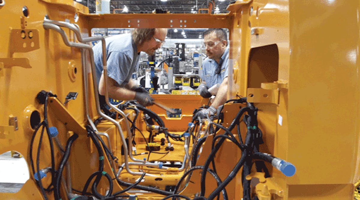 Lanny Lindsley (left) installs lower case hydraulic hoses and tubes on a skid steer loader, while Ray Perez (right) performs a quality inspection on the main chassis.