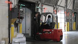 Lights in the upper corners of the interior dock doors confirm trailer restraint status as a forklift operator exits a trailer Lights in the upper corners of the interior dock doors confirm trailer restraint status as a forklift operator exits a trailer