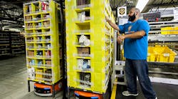 An employee picking merchandise with an Amazon robot.