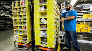 An employee picking merchandise with an Amazon robot.